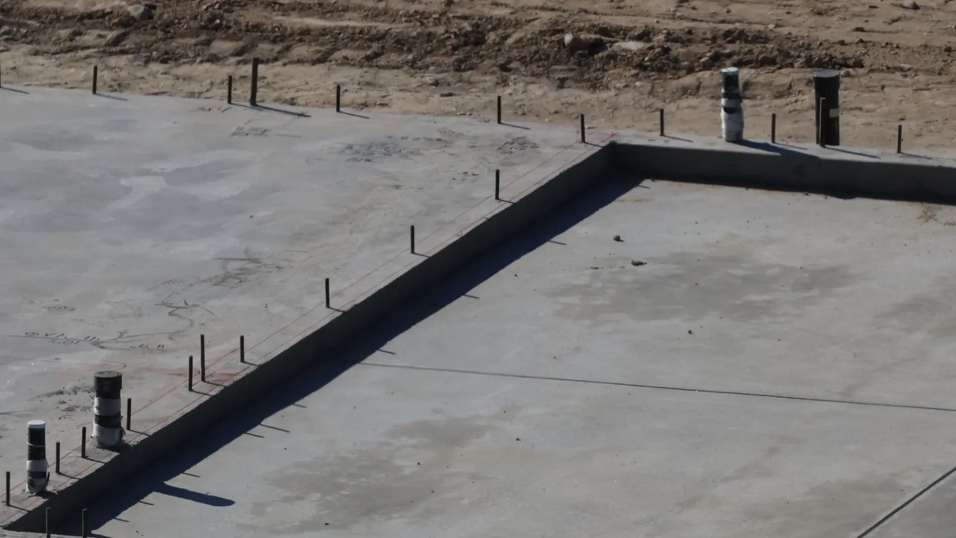 Concrete house slab with service pipes and starter bars coming through it